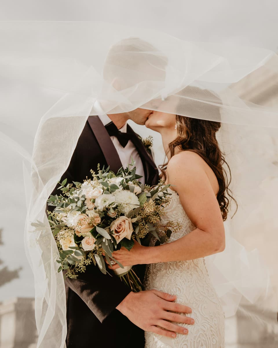 A couple kissing under a flowing veil